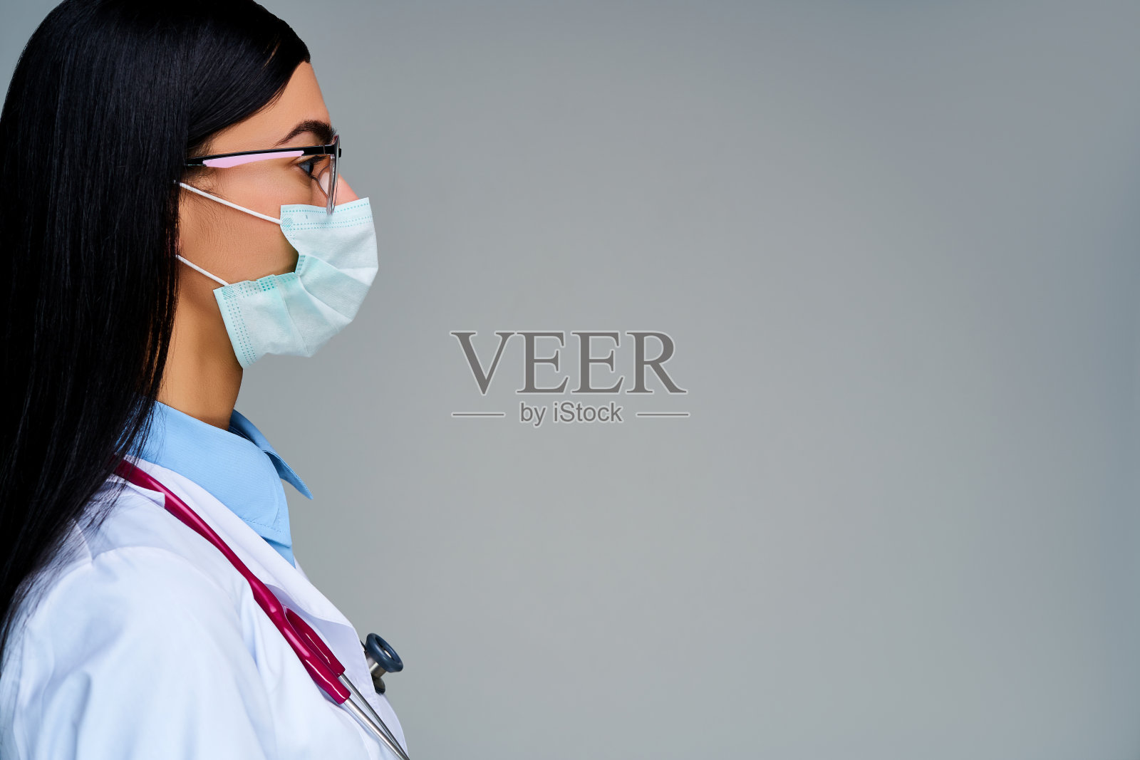 女医生戴着面罩，肩膀上戴着耳机，戴着眼镜。医学的概念照片摄影图片