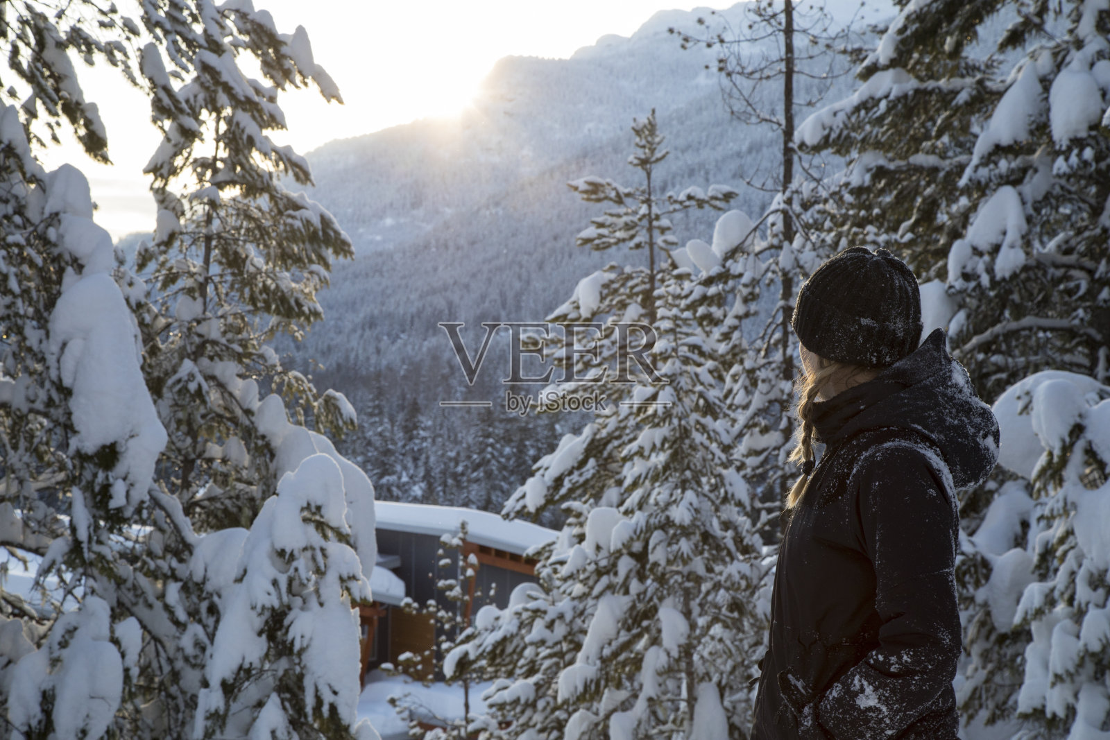 年轻女子沿着积雪的森林小径走向日出的景色照片摄影图片