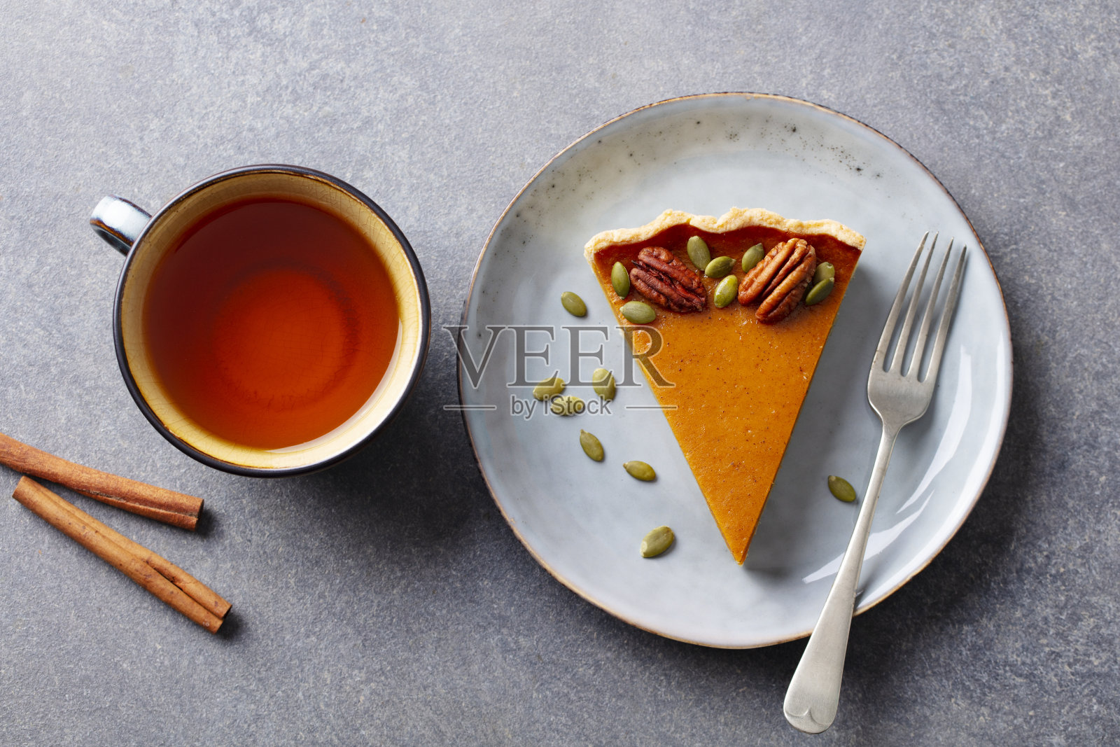 盘子里放着南瓜派和一杯茶。灰色背景。关闭了。前视图。照片摄影图片