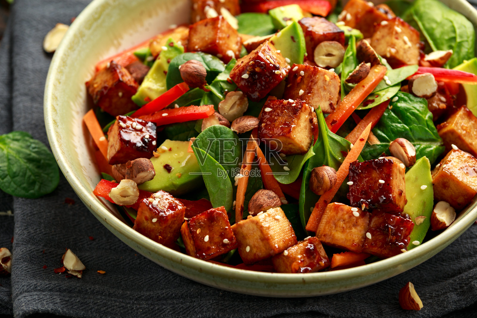健康素食炒豆腐沙拉与胡萝卜，红甜椒，菠菜和坚果照片摄影图片