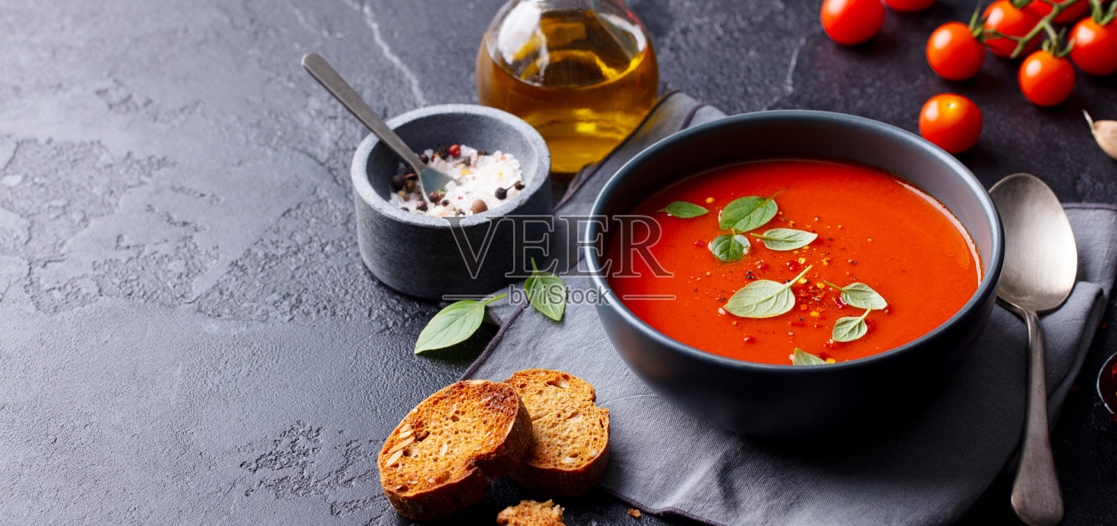 番茄汤与罗勒在碗中。灰色背景。副本的空间。照片摄影图片