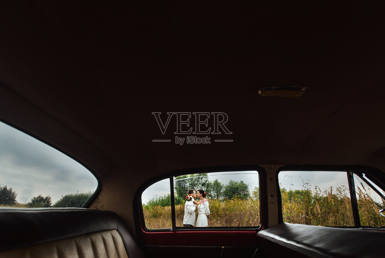 透过红色复古车看时尚新娘和幸福新郎的独特视角照片摄影图片