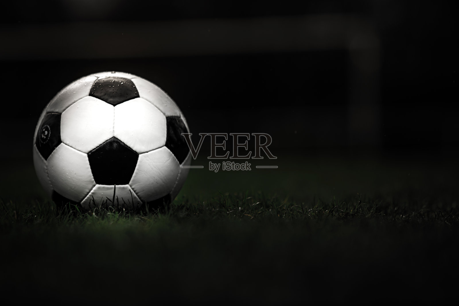 典型的黑白图案的经典足球，放置在体育场的草皮上。传统的足球在绿草如茵的草坪上有拷贝空间。照片摄影图片