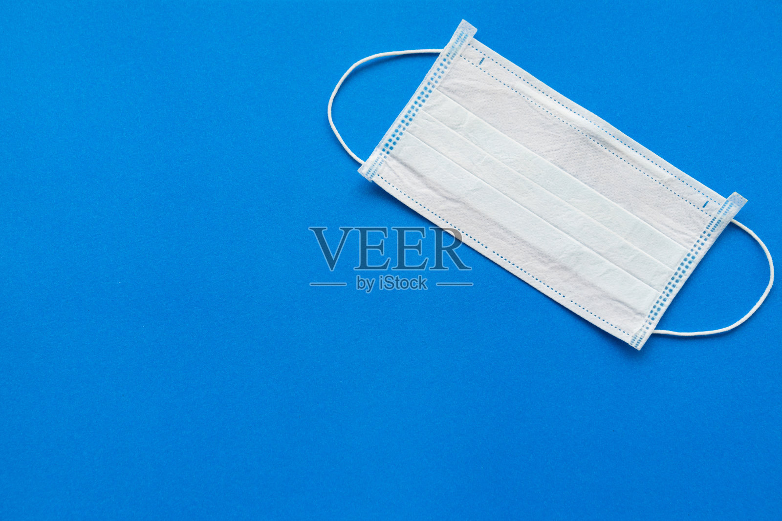 蓝色背景的一次性医用口罩。照片摄影图片