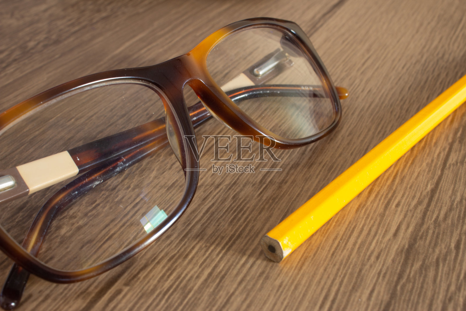 木桌上放着几只玻璃杯和一支铅笔照片摄影图片