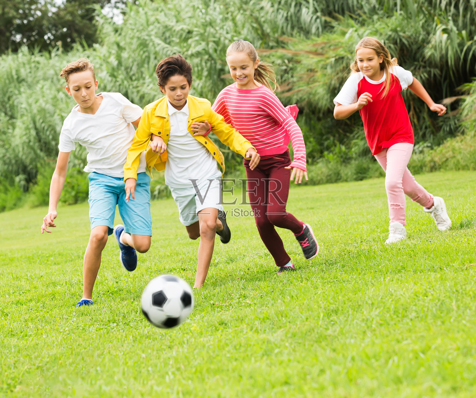 孩子们在公园里踢足球照片摄影图片