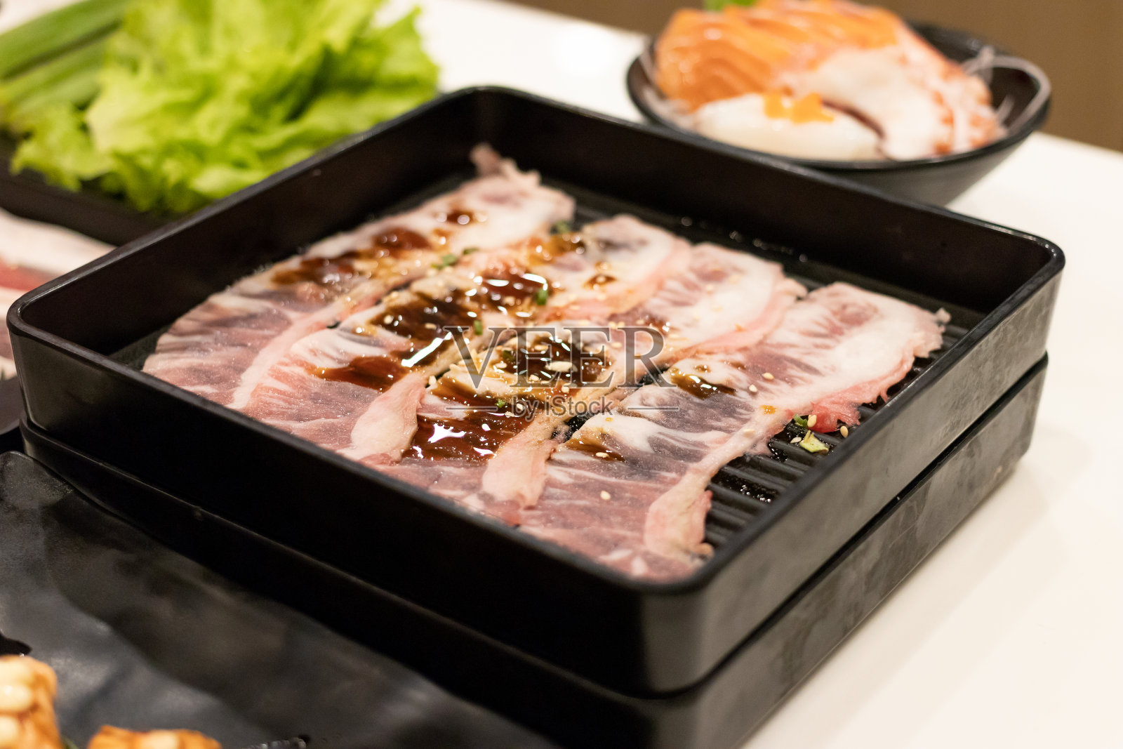 牛肉片放在黑色托盘上，用于火锅或烧烤(烧烤或烧肉)。照片摄影图片