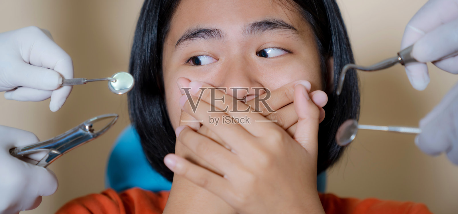 小女孩害怕牙医，在牙科诊所捂住嘴巴的特写照片摄影图片