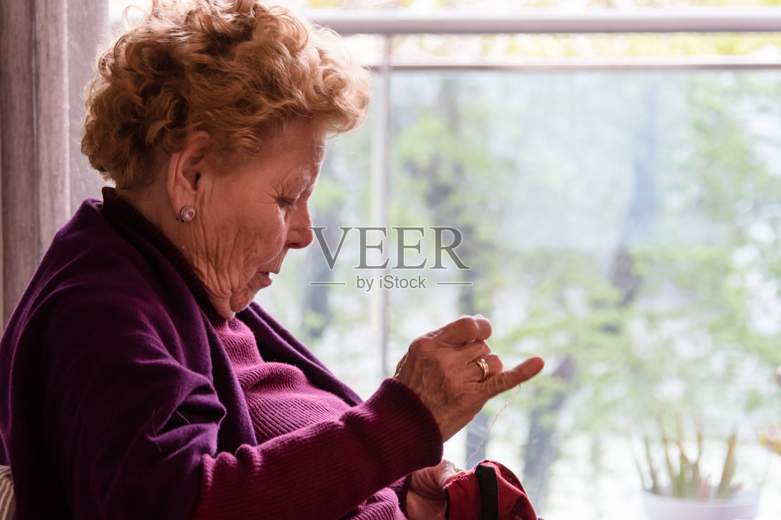 老年妇女坐在窗边缝纫照片摄影图片