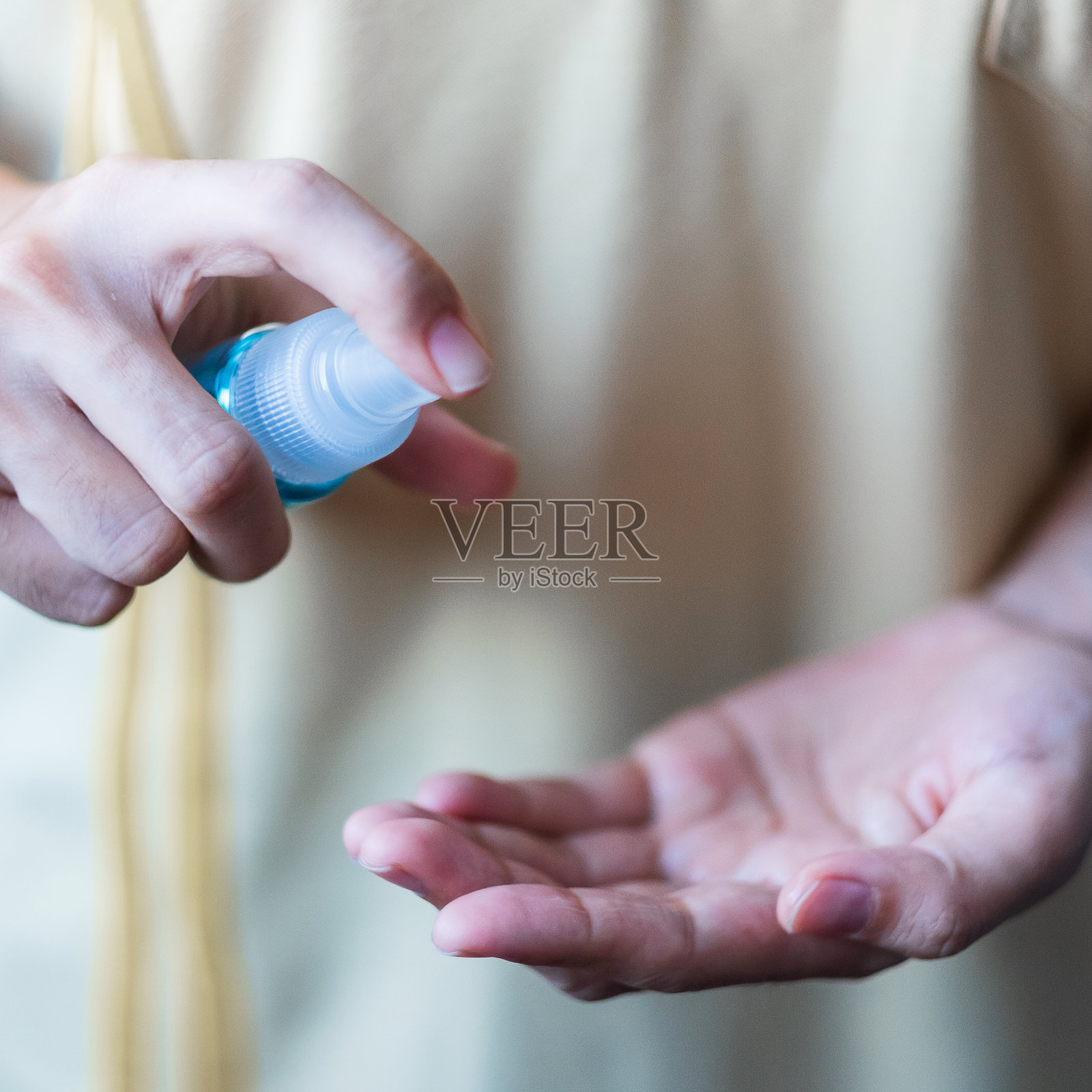 妇女在公共户外用酒精消毒剂瓶喷洒新型冠状病毒或冠状病毒疾病(Covid-19)。消毒、卫生和保健理念照片摄影图片