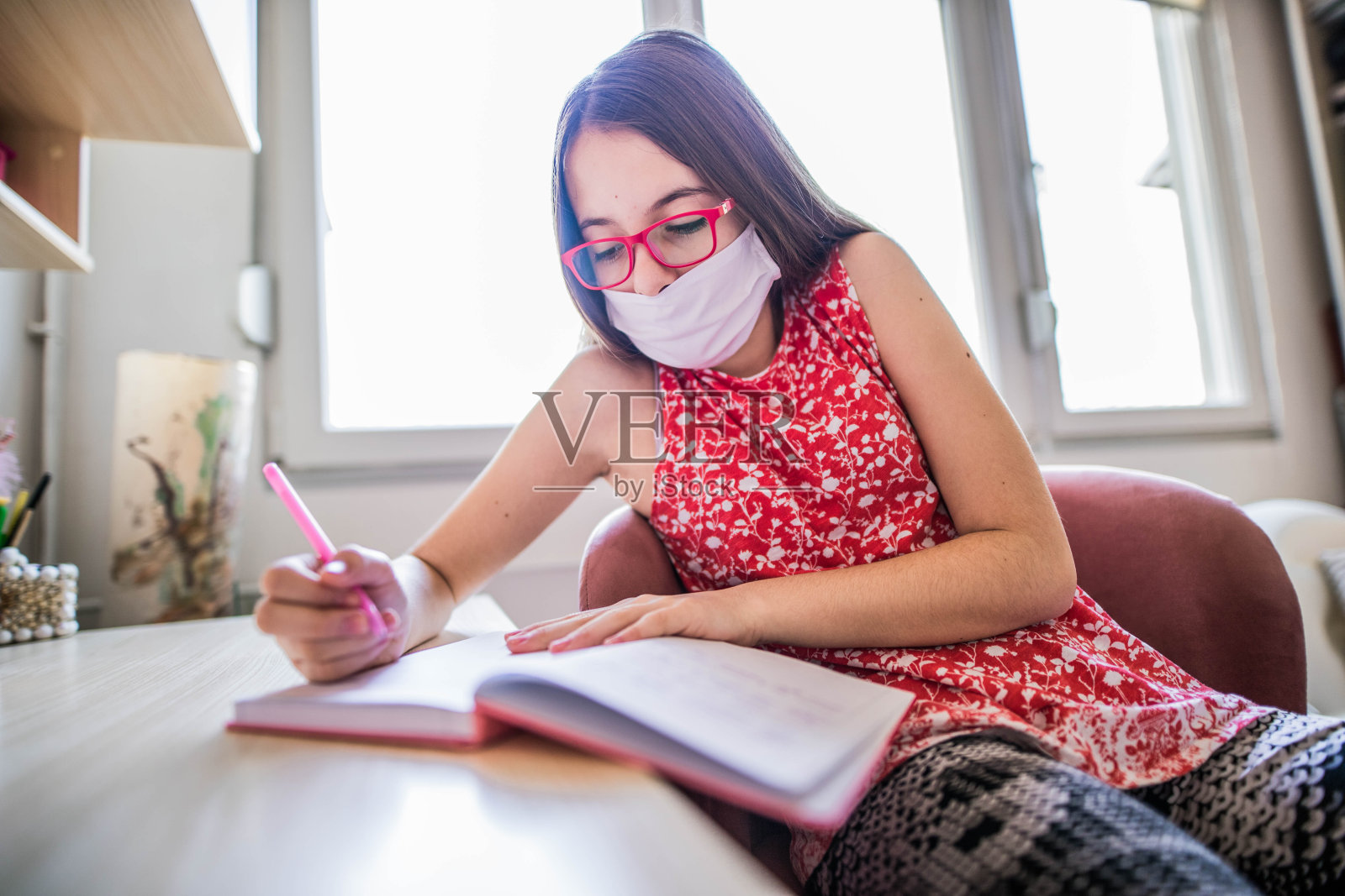 戴着医用防护口罩做作业的年轻女孩照片摄影图片