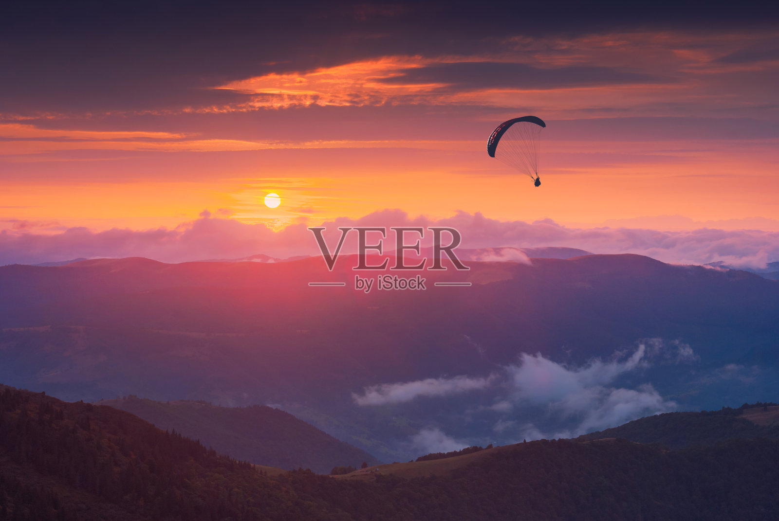 夕阳下滑翔伞的剪影照片摄影图片