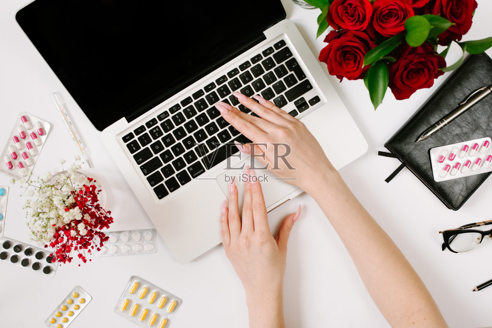 女人的手印在笔记本上。远程工作，治疗，流行病和隔离概念与玫瑰花束，笔记本电脑和笔记本电脑照片摄影图片