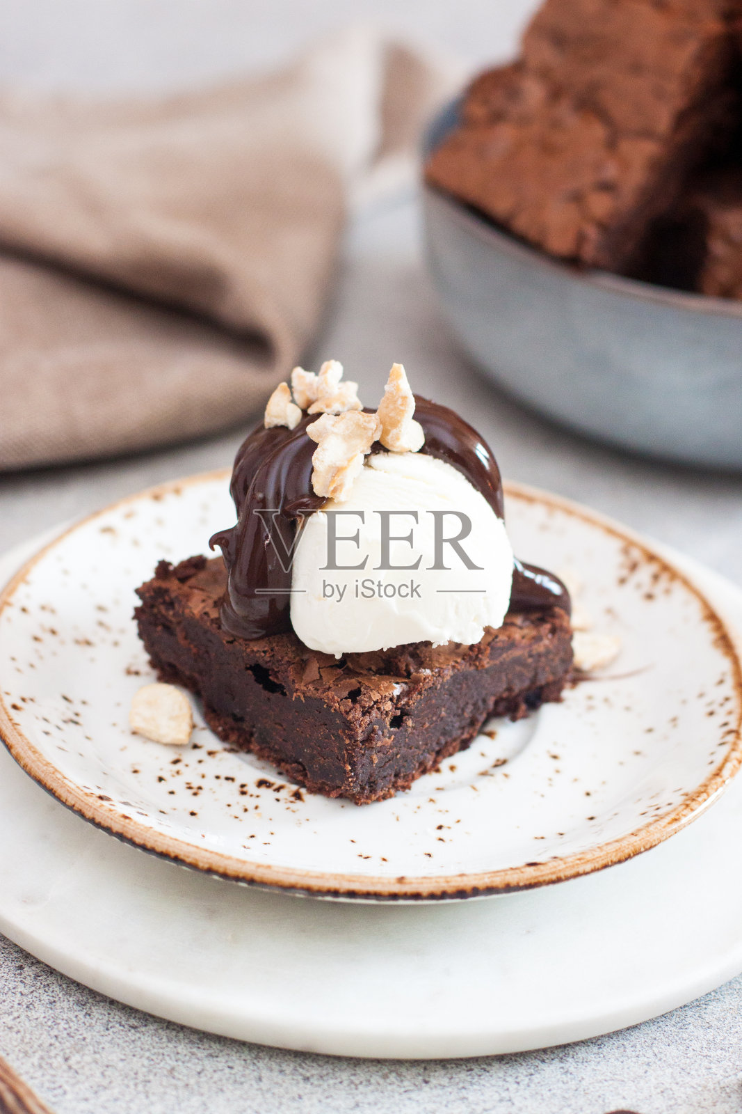 自制布朗尼配一勺香草冰淇淋，巧克力酱和坚果。灰色背景照片摄影图片