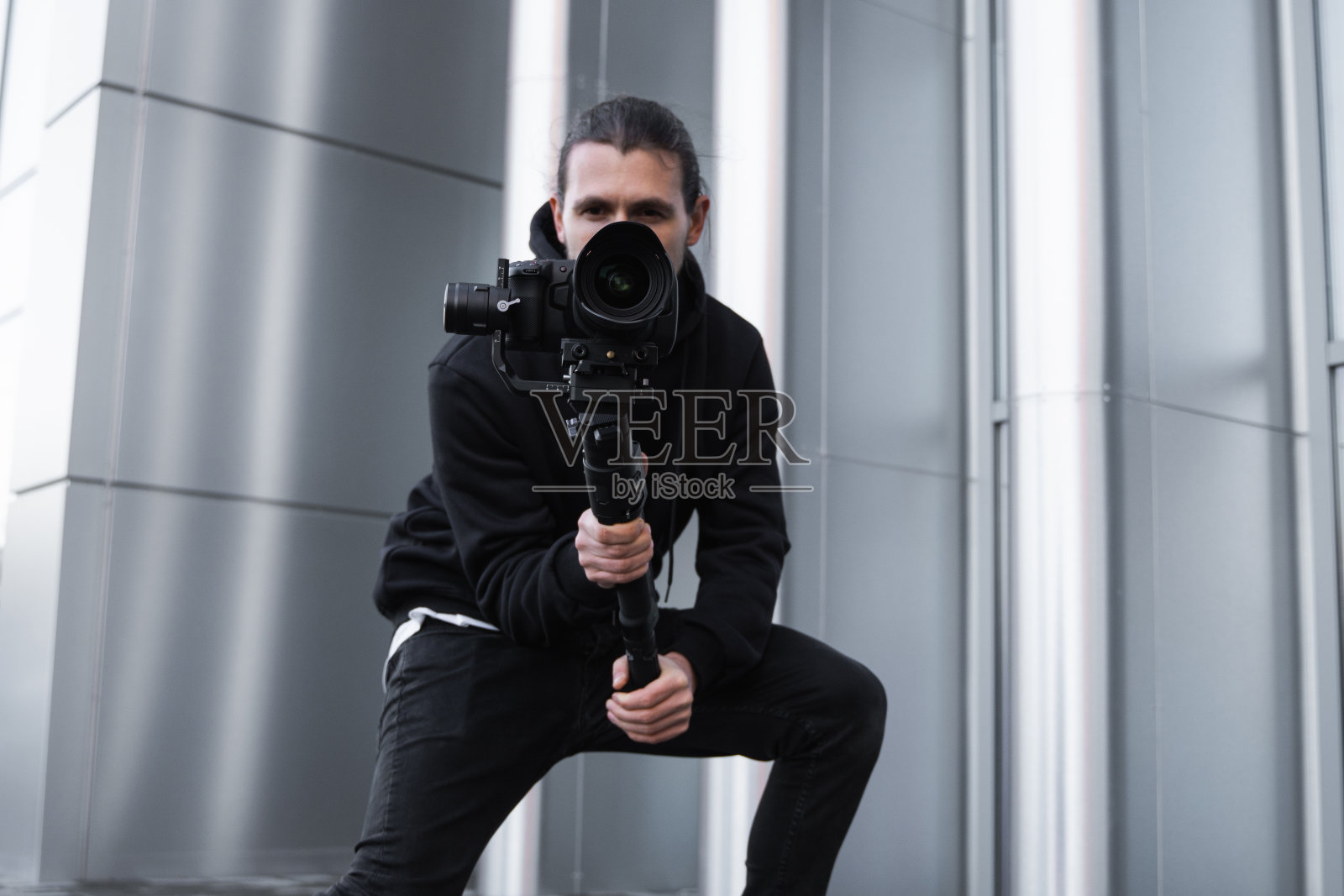 年轻的专业摄像师手持专业相机在三轴稳定器上拍摄视频照片摄影图片