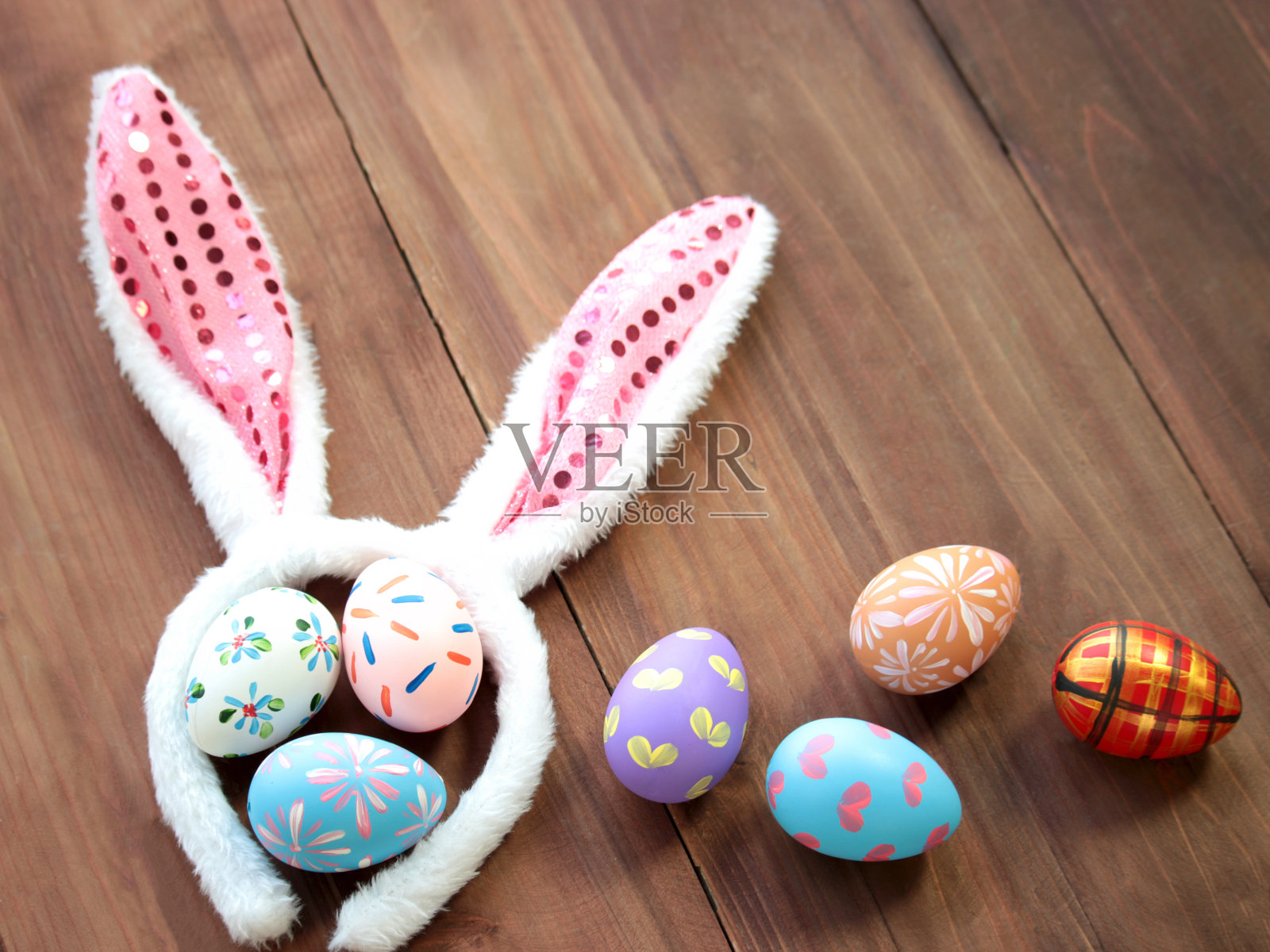 五彩缤纷的复活节彩蛋配兔耳帽在木制背景上，节日和节日的春天来临，复活节校准照片摄影图片