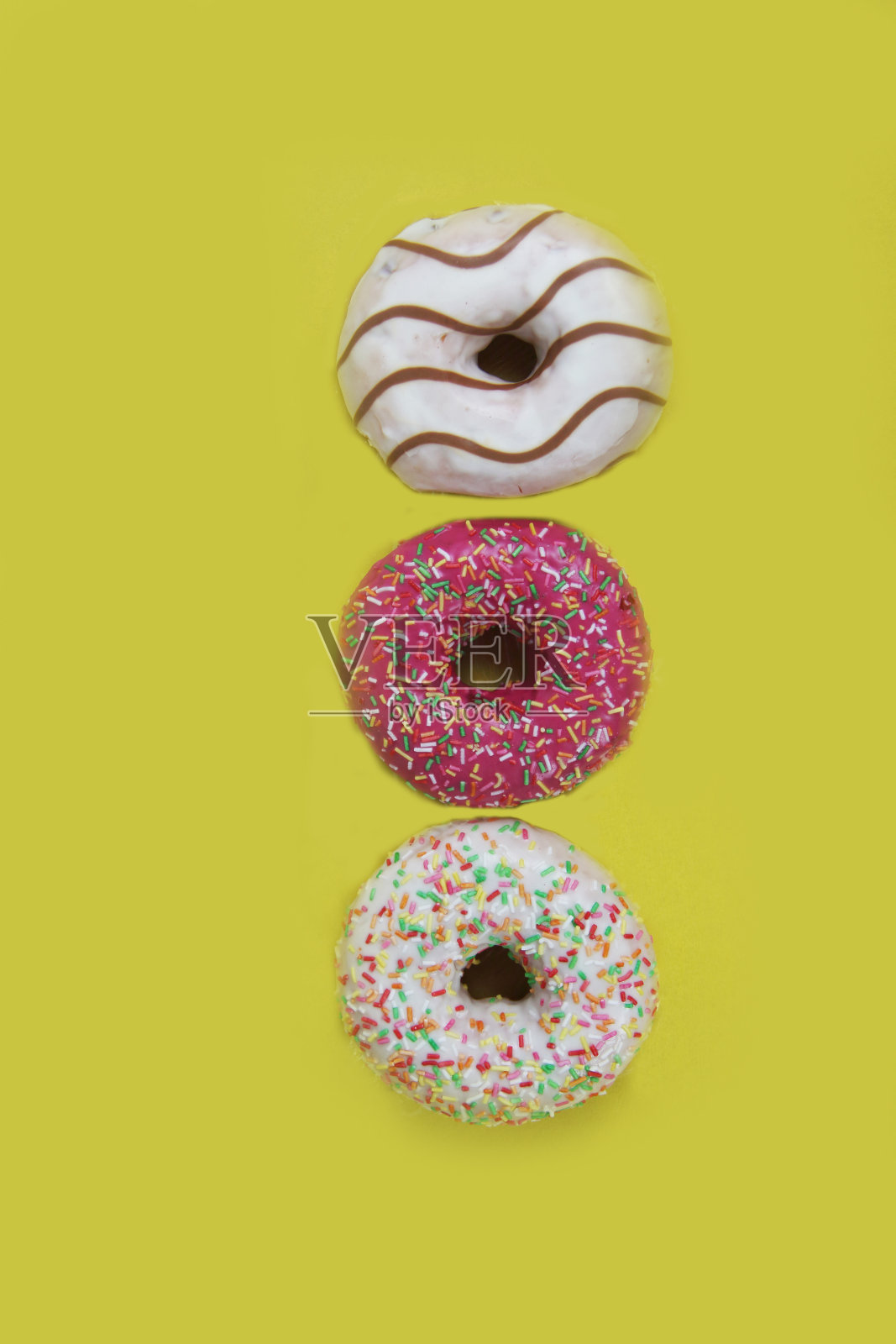 三个甜甜圈被孤立在黄色的背景上照片摄影图片