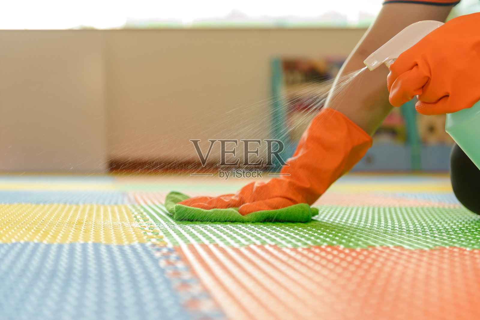 女士手持橙色防护橡胶手套，手持绿色超细纤维清洁布，用喷雾式消毒液擦拭灰尘，保持清洁消毒的良好卫生照片摄影图片