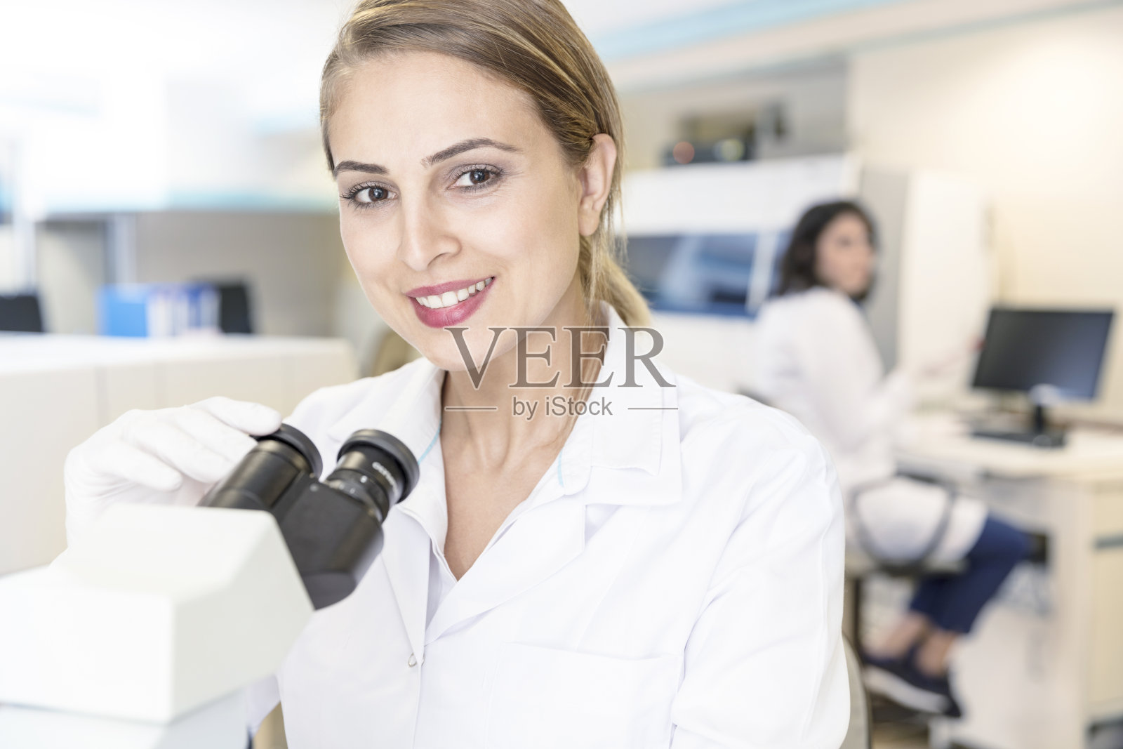 在实验室使用显微镜工作的妇女照片摄影图片