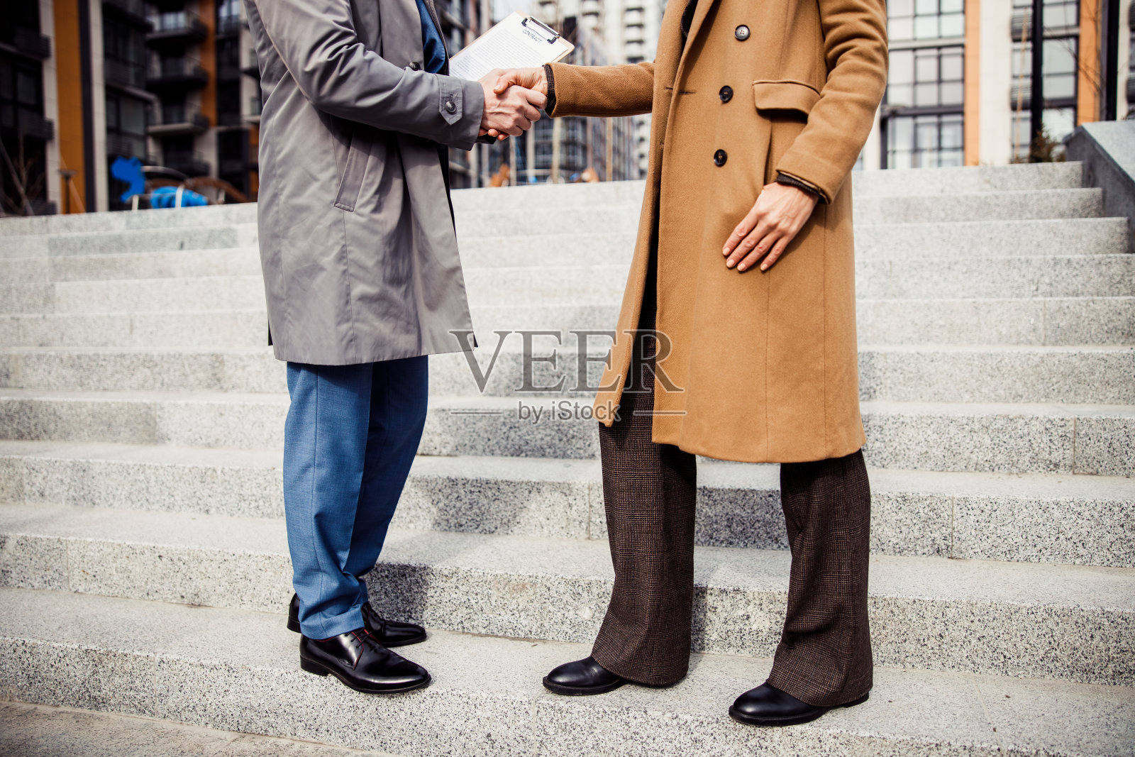 一名男子拿着文件向一名女企业家打招呼照片摄影图片