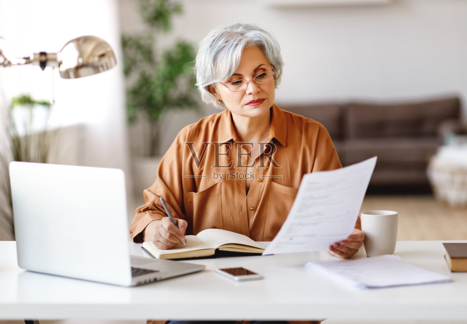 资深女性在家做文书工作照片摄影图片