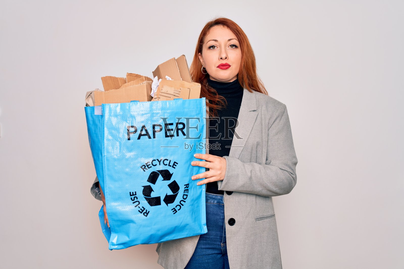 年轻漂亮的红发女人回收拿着纸袋纸板回收与自信的表情在聪明的脸上思考认真照片摄影图片