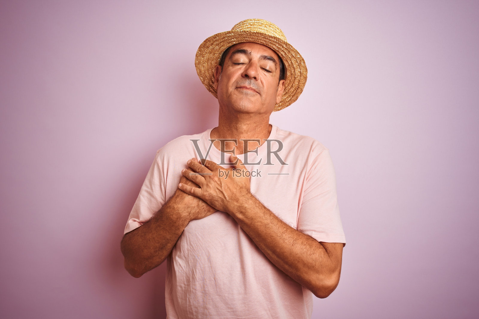 戴着夏帽的中年男人面带微笑，双手合十，闭着眼睛，心怀感激照片摄影图片