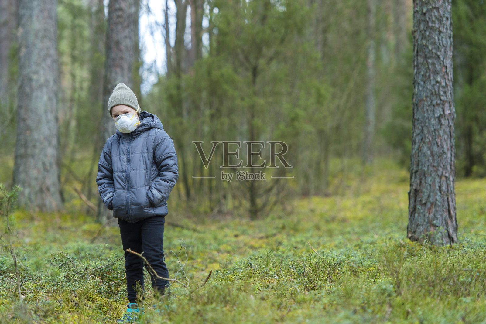失望孤独的孩子戴着防毒面具在空旷的森林里传播冠状病毒。照片摄影图片