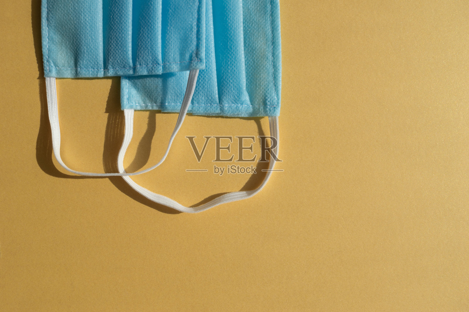 2个淡蓝色医用一次性口罩，亮黄色背景，对抗2019冠状病毒。医疗理念、隔离、遏制冠状病毒照片摄影图片