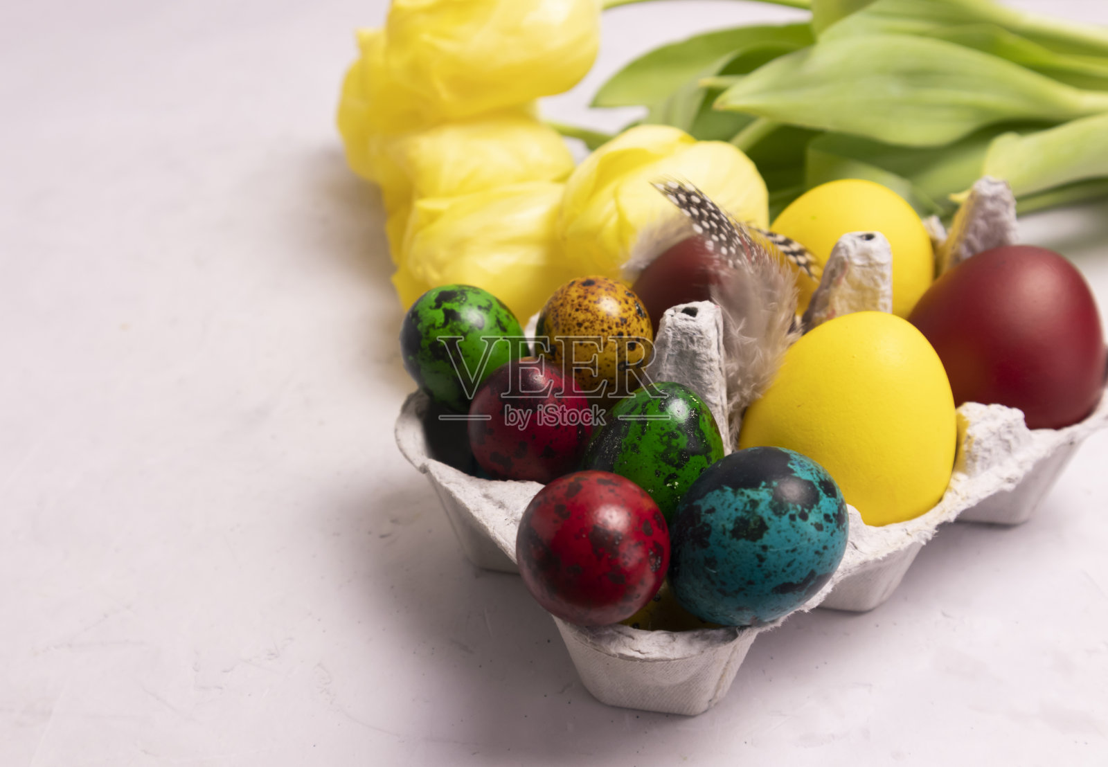 郁金香和一个放着彩色复活节彩蛋的托盘，水平摆放照片摄影图片