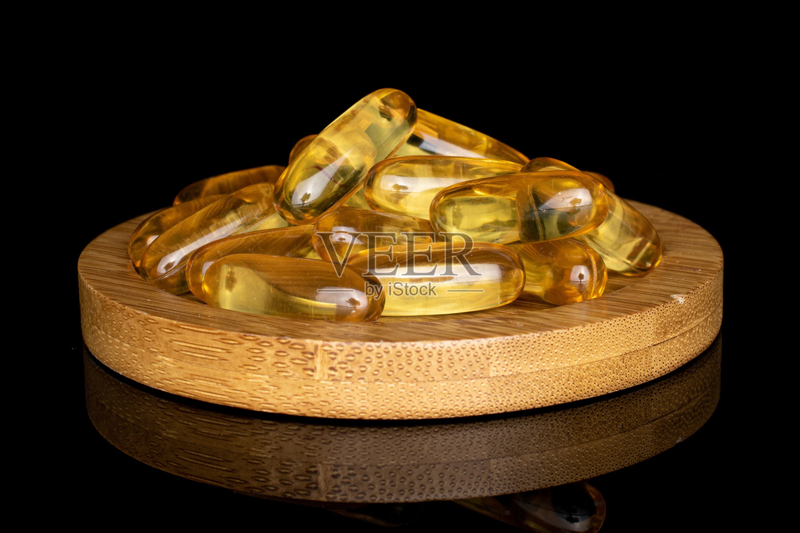 金色鱼油隔离在黑色玻璃上照片摄影图片