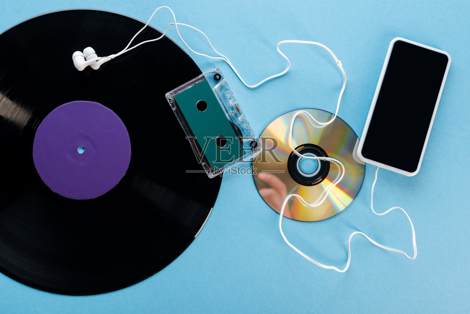 俯视图古董黑胶唱片，光盘，耳机，磁带和智能手机与空白屏幕上的蓝色，演变概念照片摄影图片