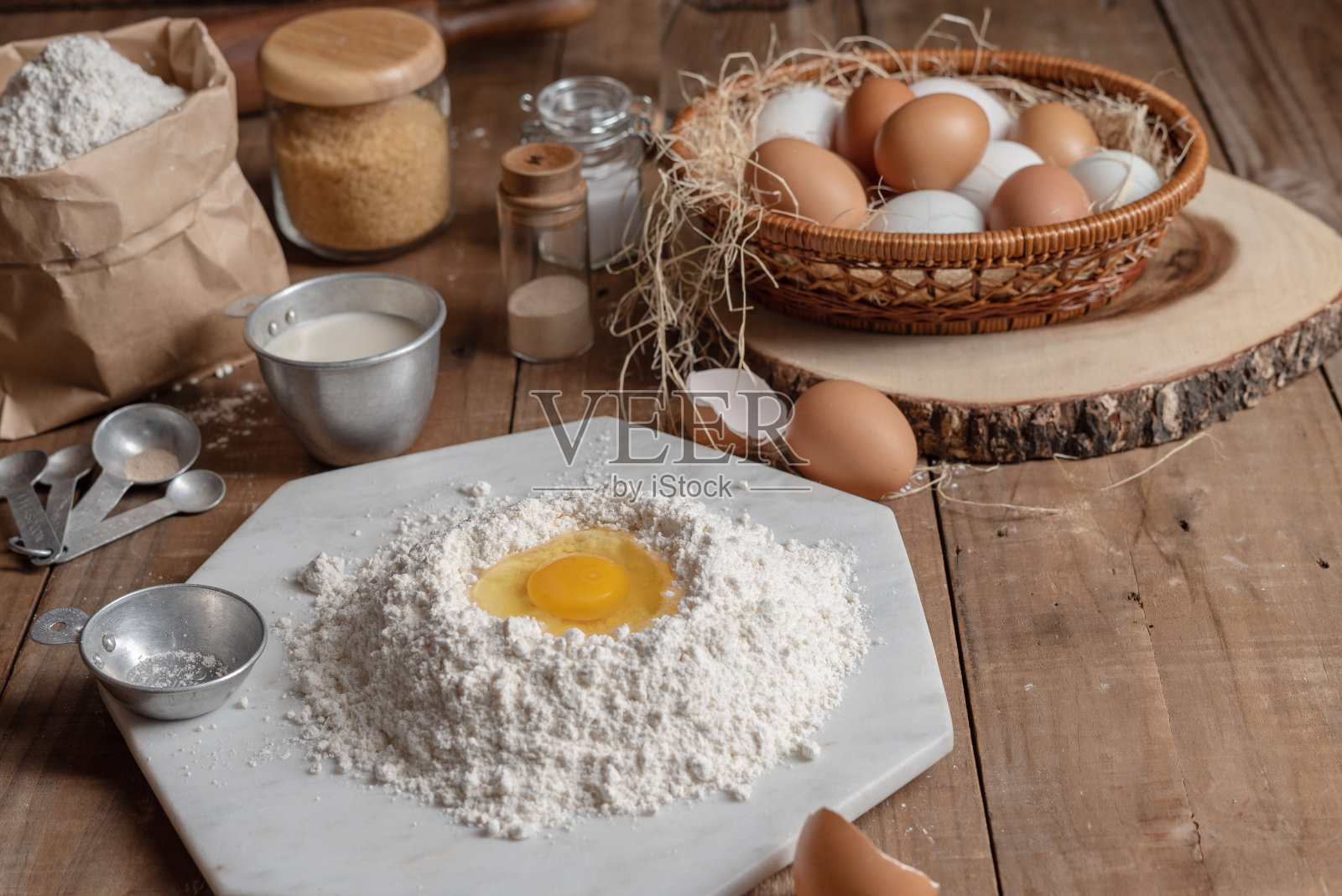 面粉和蛋黄和篮子里放了很多鸡蛋放在木桌上煮东西。照片摄影图片