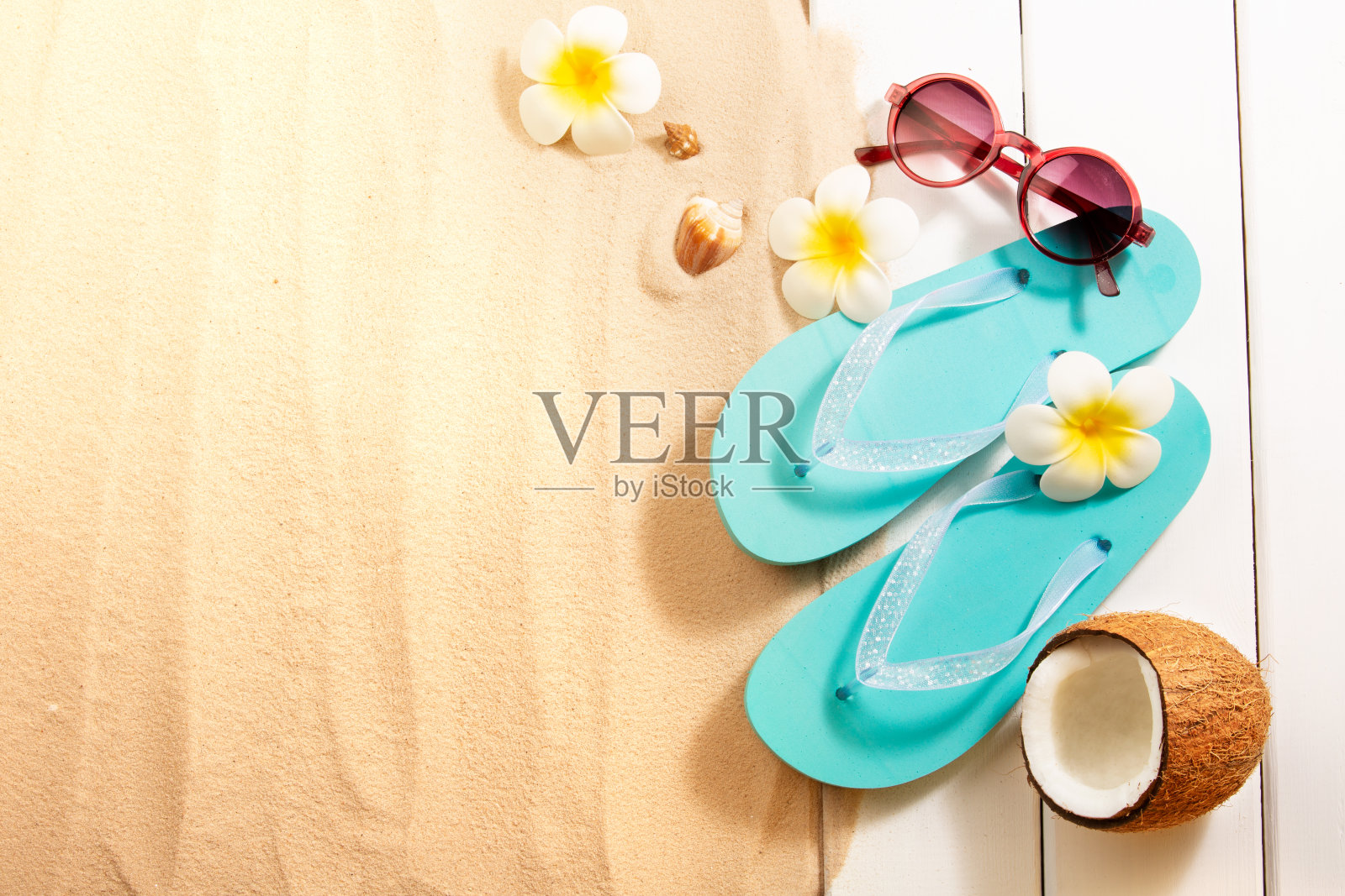 暑假。蓝色拖鞋，太阳镜，椰子和其他沙滩配件上的沙子和白木背景。顶部视图与复制空间。照片摄影图片