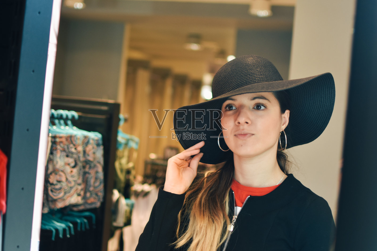 微笑的女试穿新帽子看镜子反射照片摄影图片