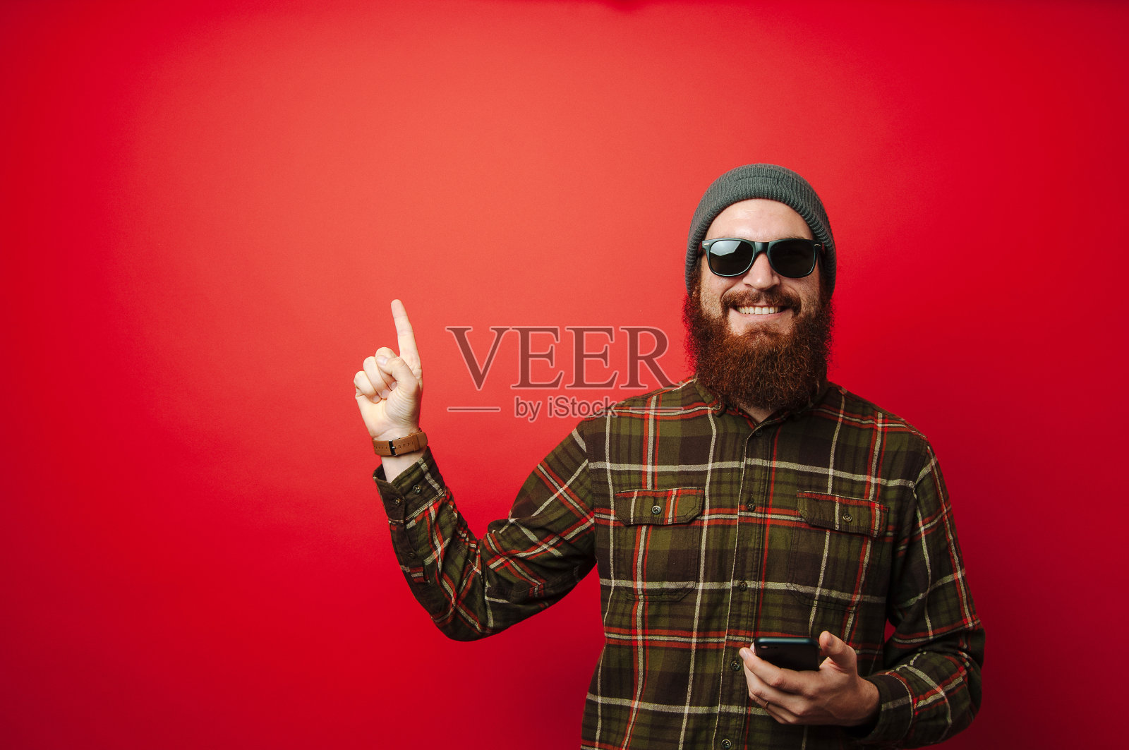 年轻快乐的大胡子男人拿着电话，指着上面的复印区照片摄影图片