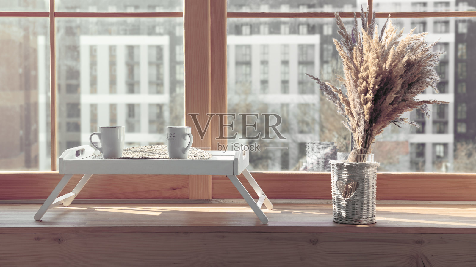 上菜桌上放着两只白色杯子，上面放着花，窗台上还有花瓶照片摄影图片
