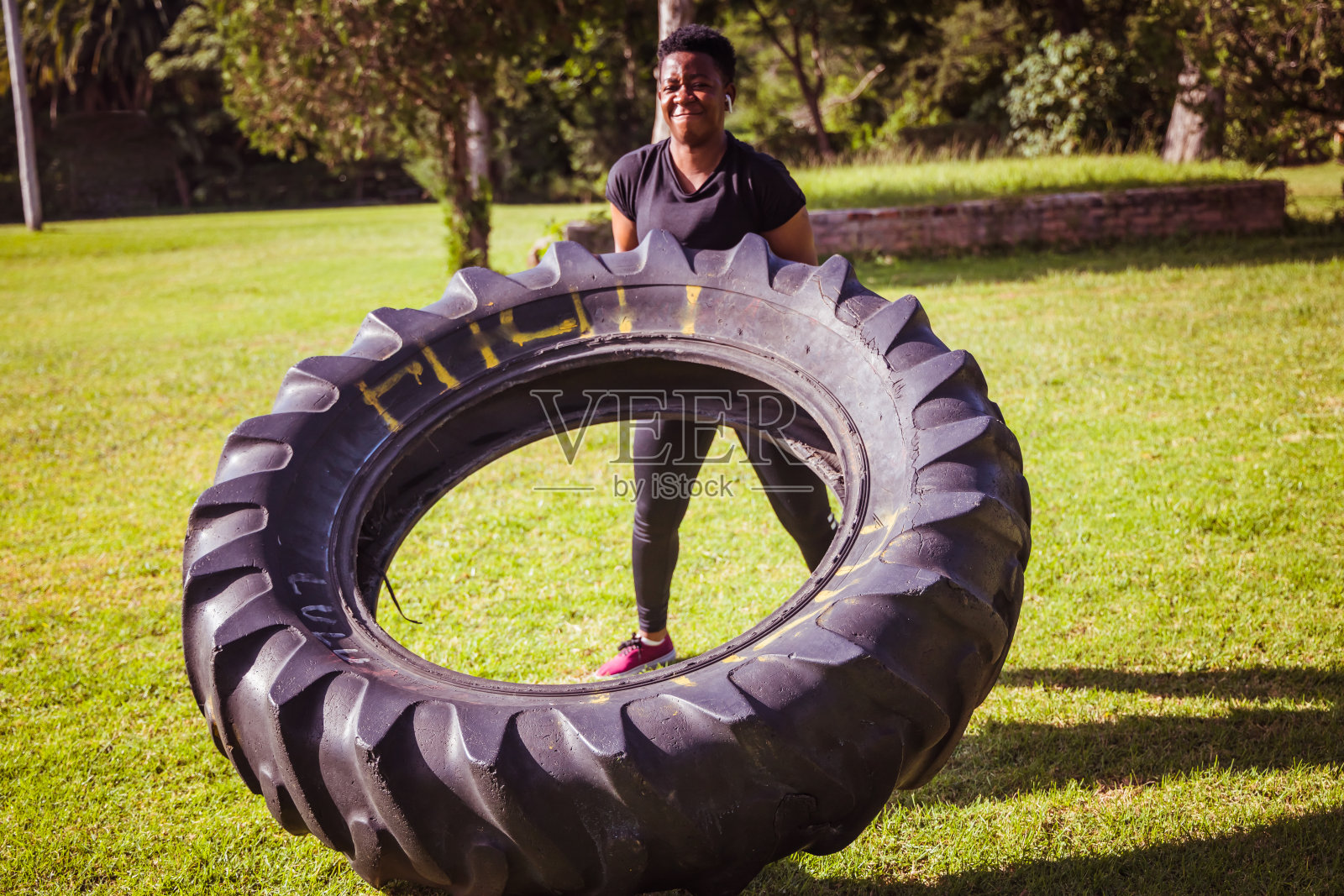 美丽的运动员女孩有一个举重训练和工作与一个大轮胎在公园股票照片照片摄影图片