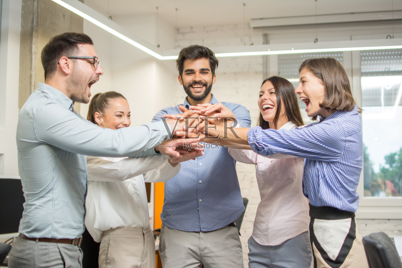 团结的商务同事在办公室里手牵手站在一起照片摄影图片