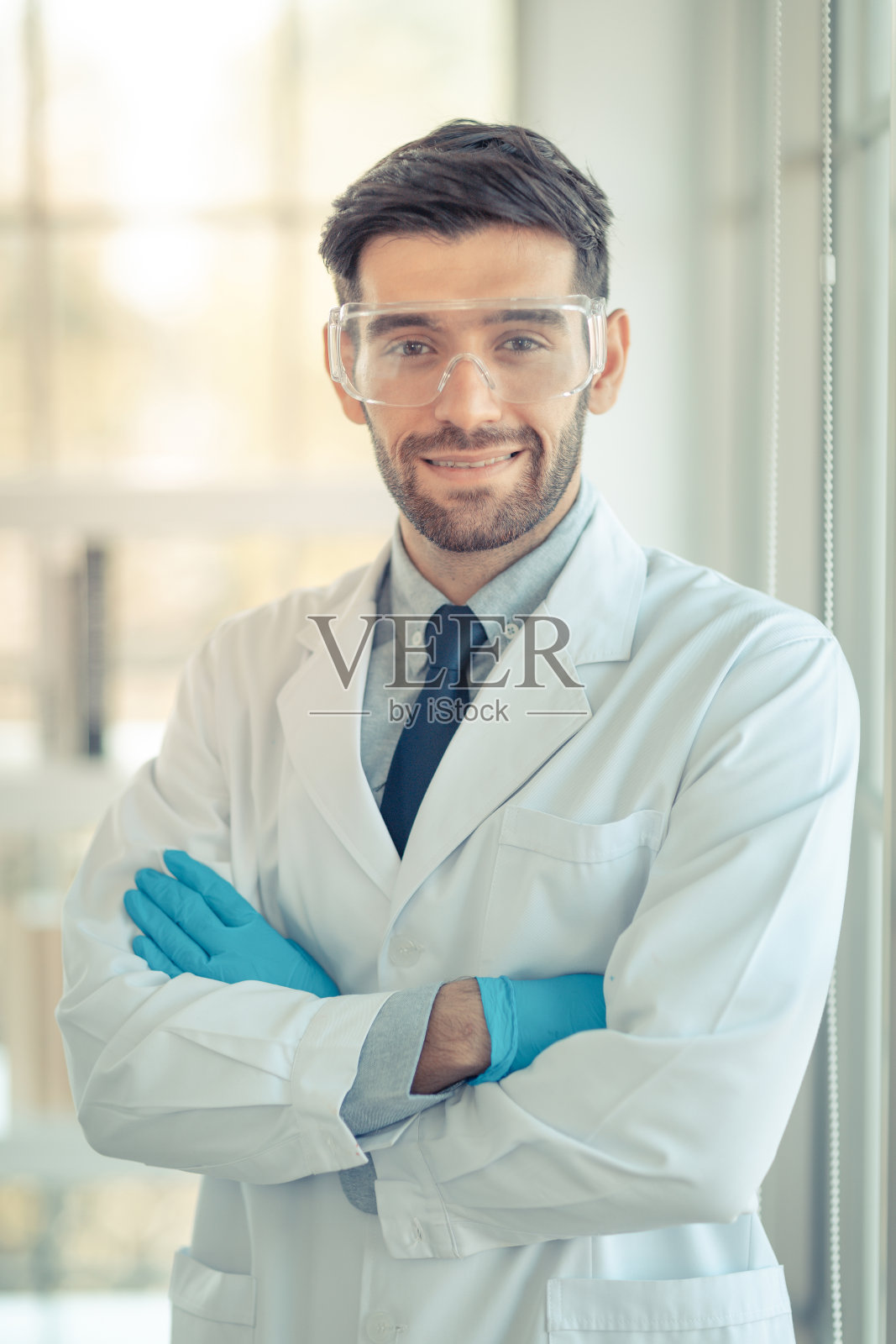 男医生穿着白大褂，对着窗户微笑，照片摄影图片