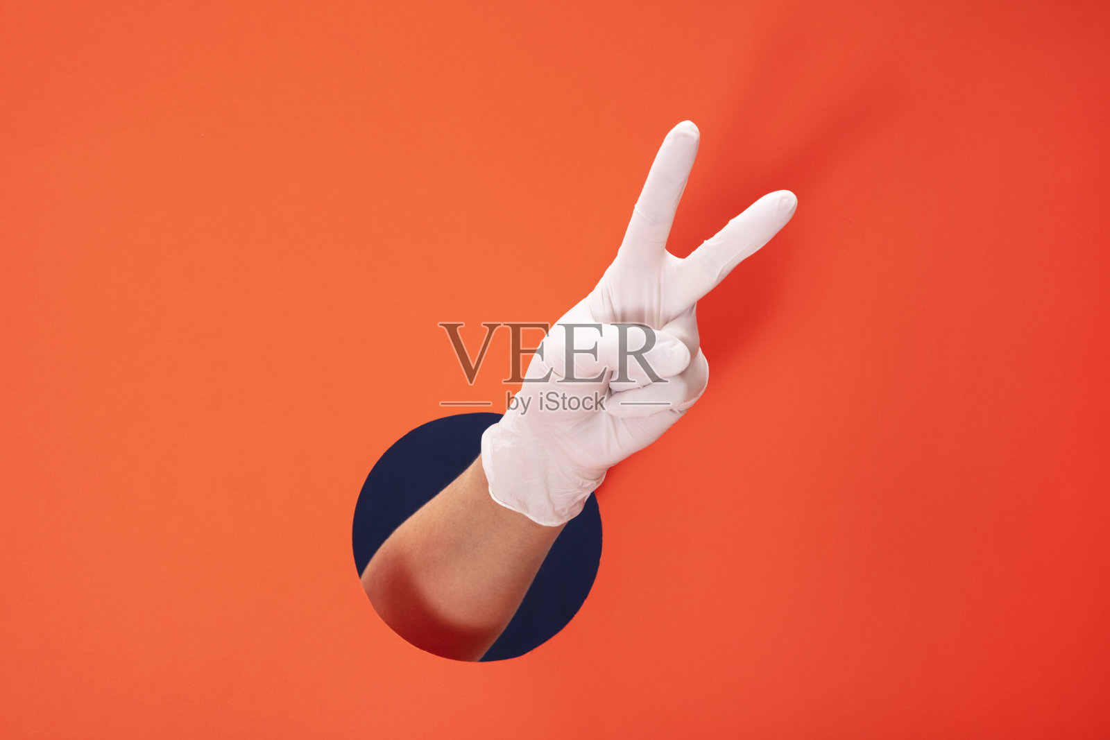 医生手与白色医疗手套显示数字2在橙色纸背景照片摄影图片