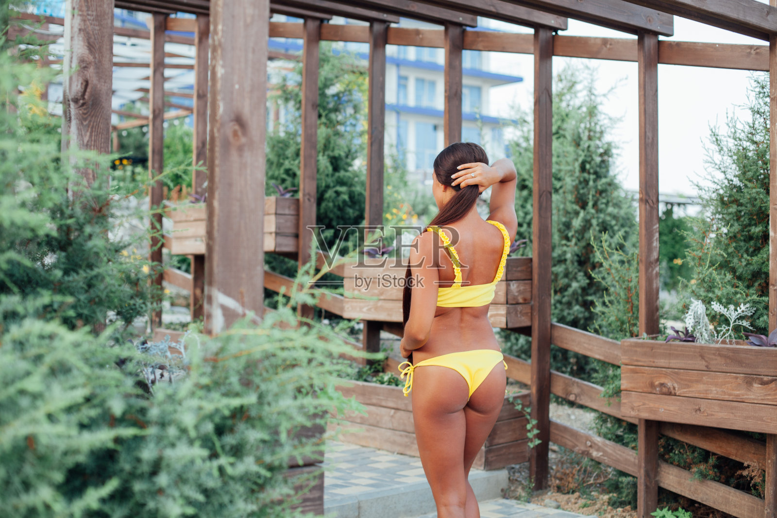 在海边的沙滩上，穿着黄色泳衣的古铜色女人留着长发照片摄影图片