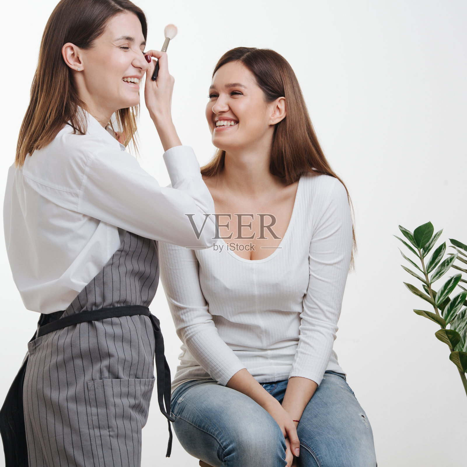 在一个明亮的房间里，女造型师拿着粉刷和她的客户聊天照片摄影图片