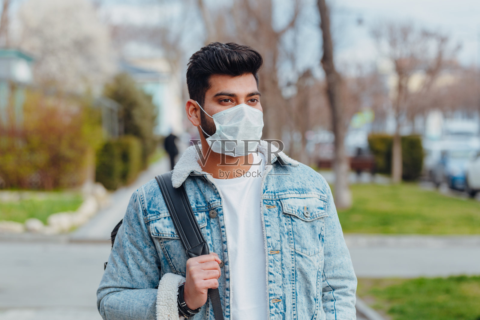 穿着时髦的印度年轻男子戴着医用口罩走在街上。卫生口罩，以预防感染，空气传播的呼吸道疾病，如流感或2019-nCoV照片摄影图片