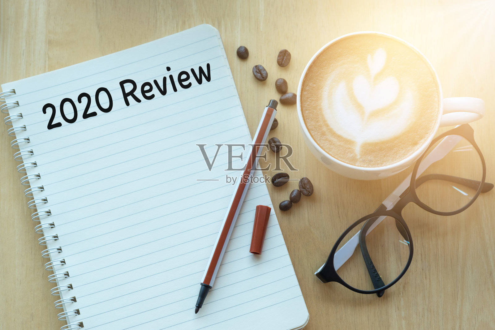 2020年回顾信息在笔记本上，眼镜，铅笔和咖啡杯放在木桌上。照片摄影图片