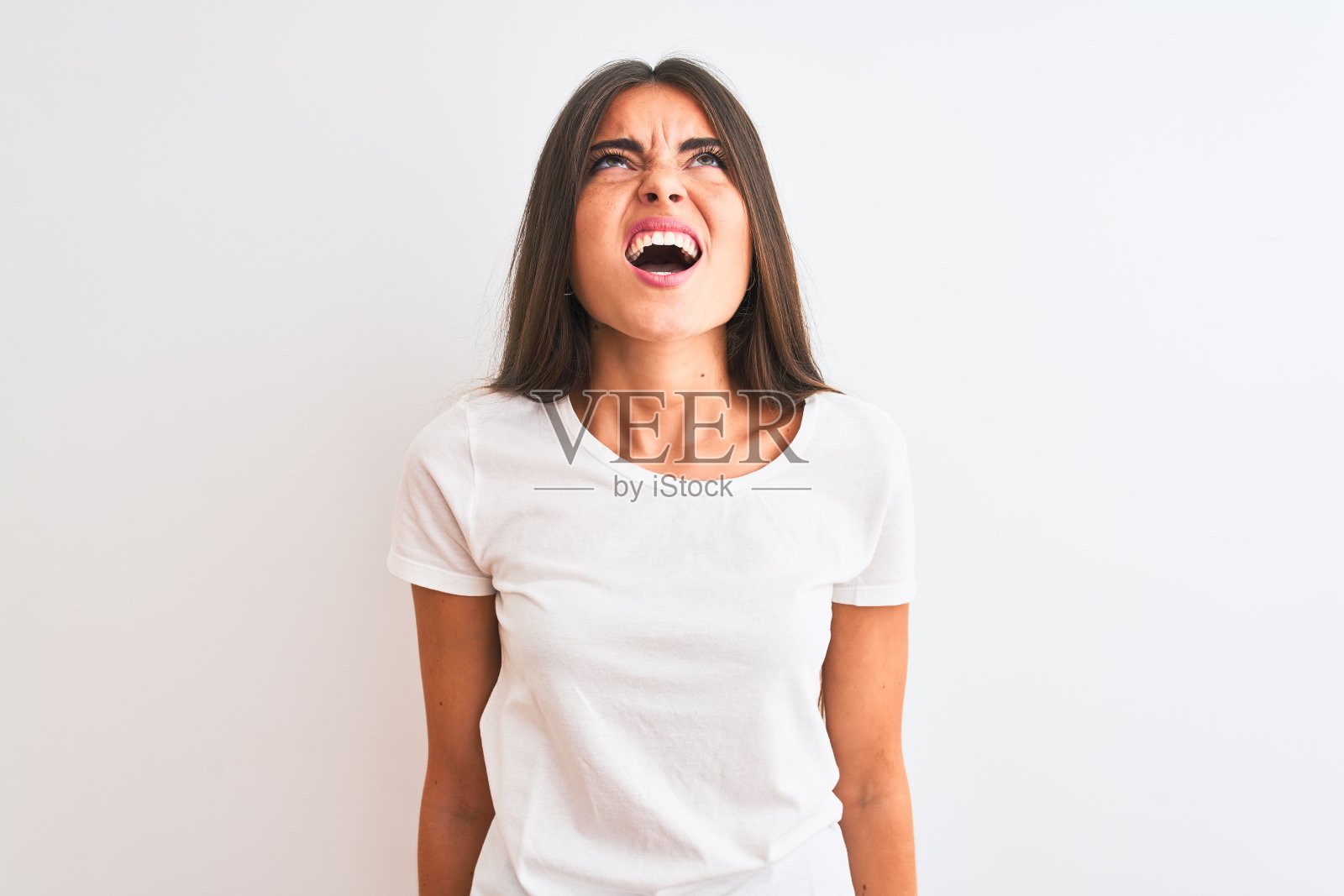 年轻美丽的女人穿着休闲t恤站在孤立的白色背景愤怒和疯狂的尖叫沮丧和愤怒，大喊与愤怒。愤怒和侵略性的概念。照片摄影图片