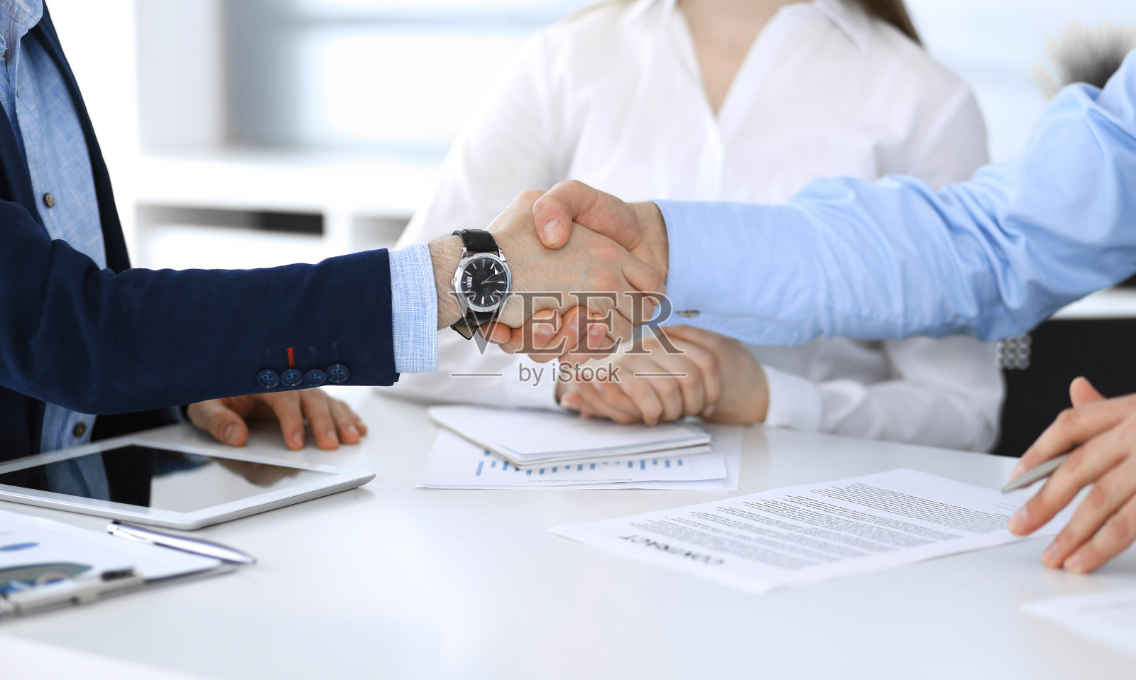 商务人士在会议或谈判中握手，特写。一群不知名的商人和女性在现代办公室。团队合作，伙伴关系和握手的概念，色调图片照片摄影图片