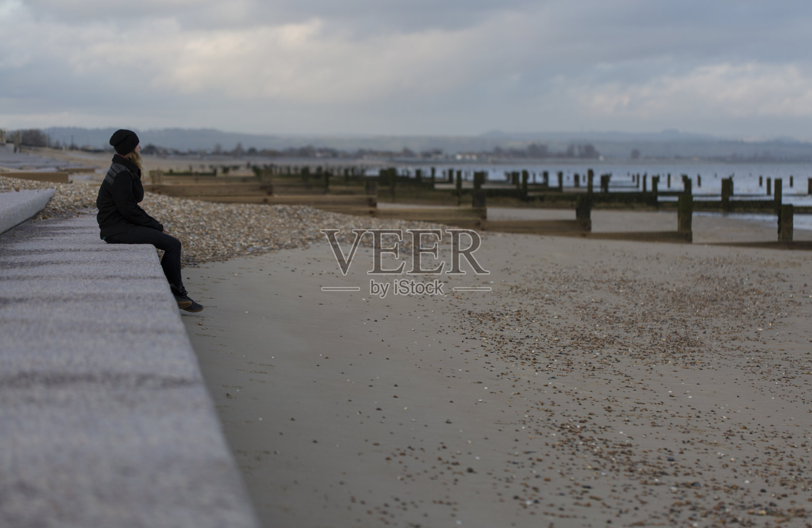 独自一人坐在荒凉海滩上的女人照片摄影图片