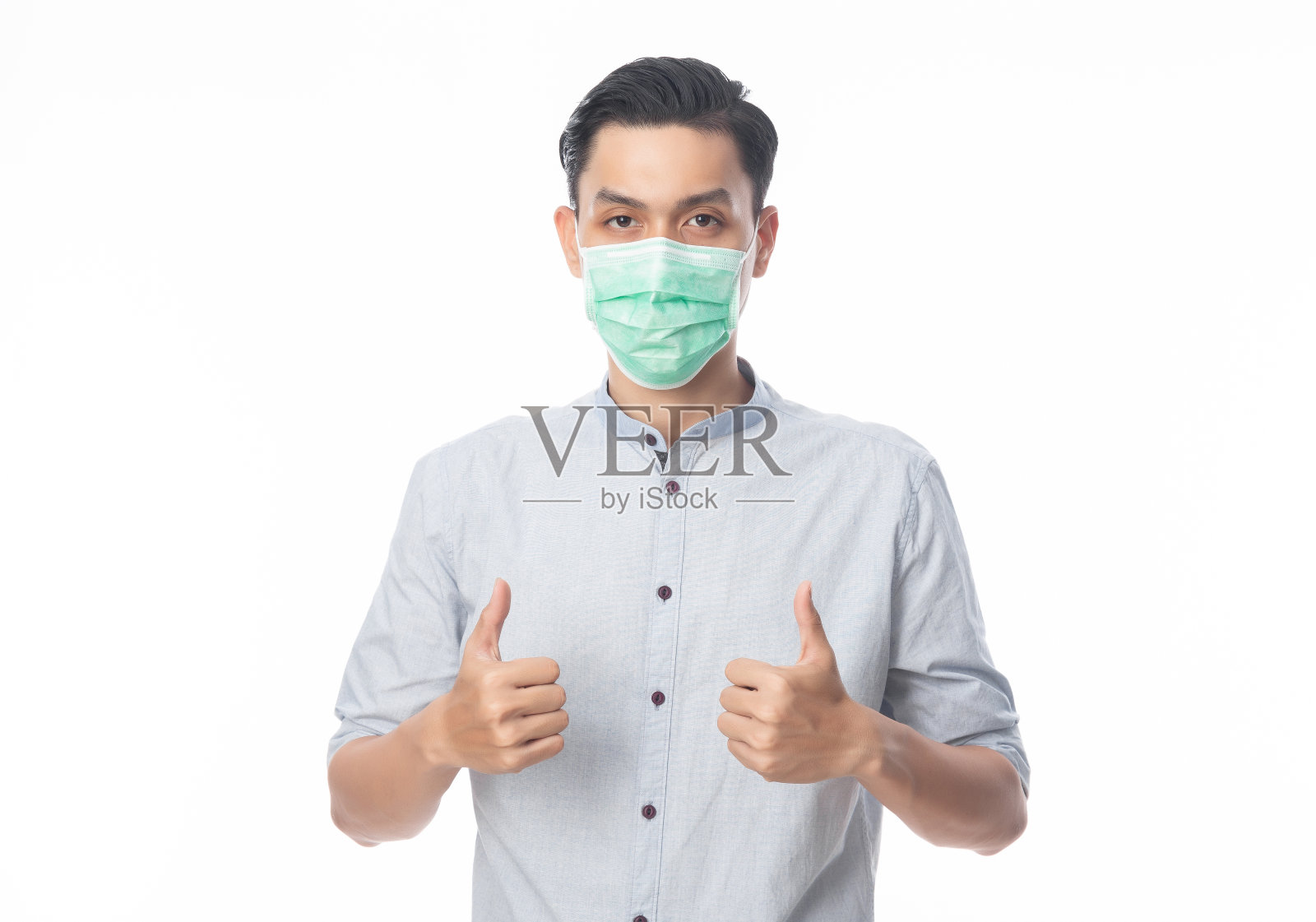 年轻的亚洲商人戴上卫生口罩，竖起大拇指，以防止感染新型冠状病毒或冠状病毒。空气传播的呼吸系统疾病，如pm 2.5战斗和流感隔离在白色背景照片摄影图片