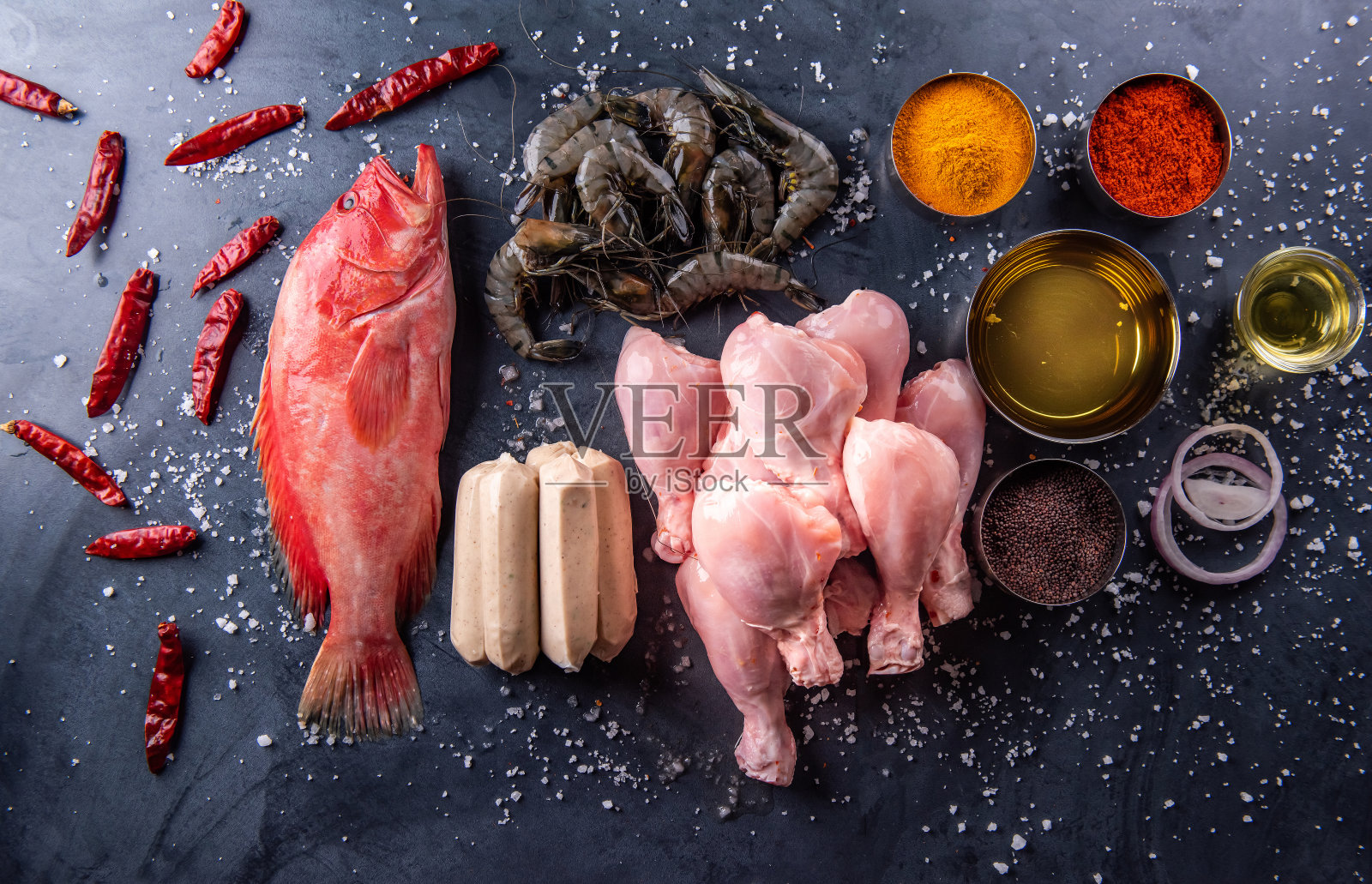 厨房的桌上放着生鸡肉、鱼和香料。照片摄影图片